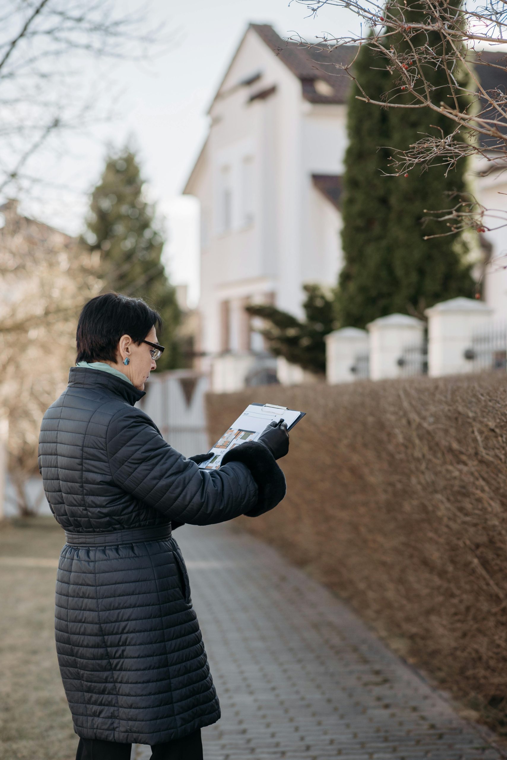A real estate agent examines house plans while standing outside.